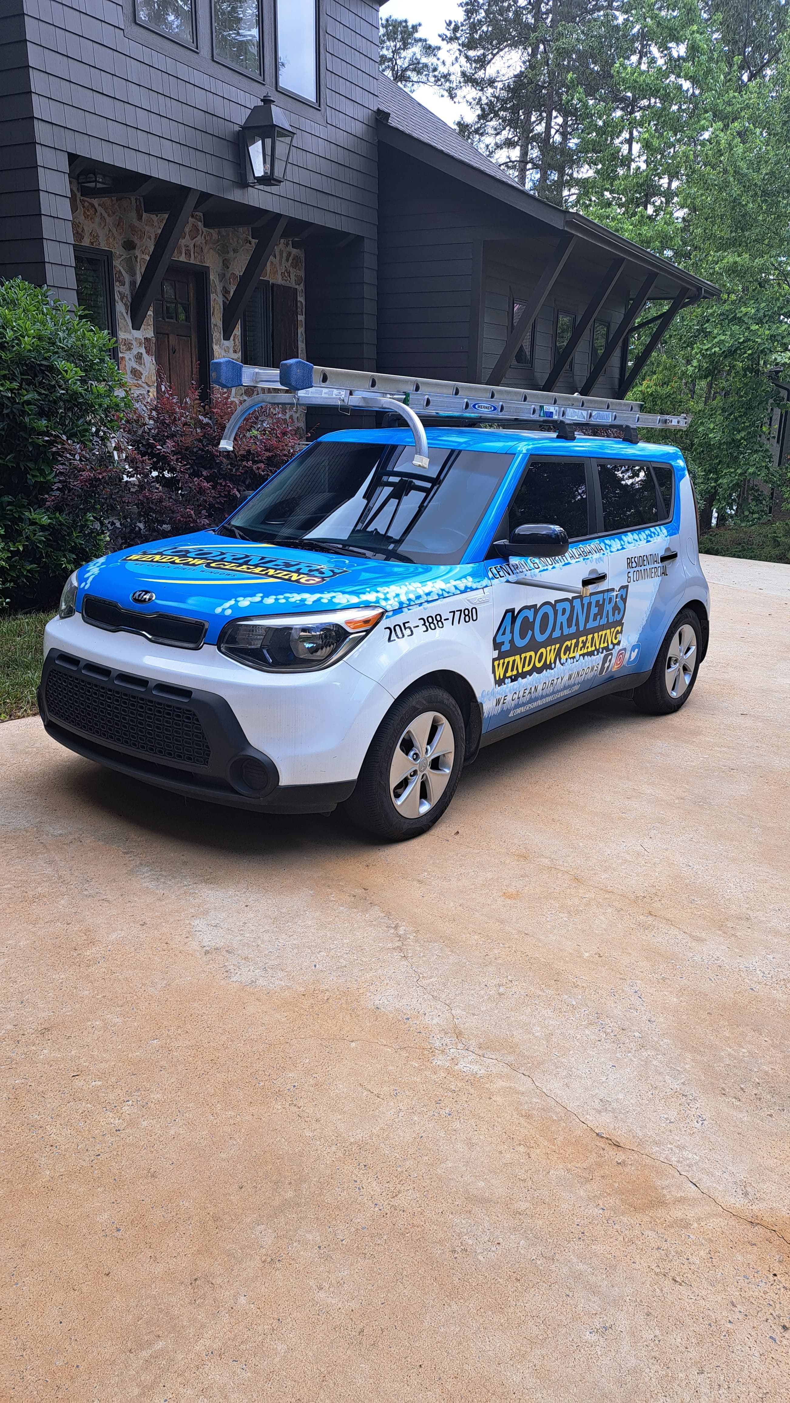 Branded 4Corners Window Cleaning Kia Soul with a roof-mounted ladder parked on a driveway.